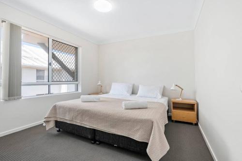 a white bedroom with a bed and a window at Bay Lodge - Private Apartments in Gold Coast