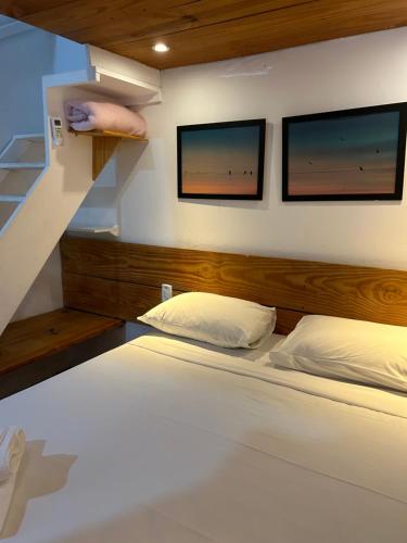 1 dormitorio con 1 cama con 2 monitores en la pared en Pousada Bar Café Algas Marinhas en Praia do Forte