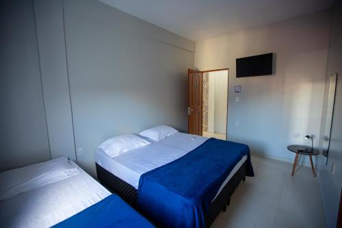 1 dormitorio con 2 camas, mesa y TV en Solare Hotel, en Barcarena