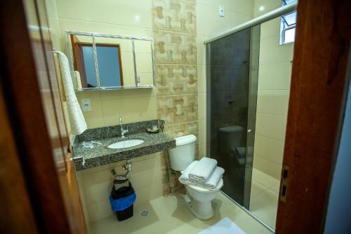 y baño con aseo, lavabo y espejo. en Solare Hotel, en Barcarena