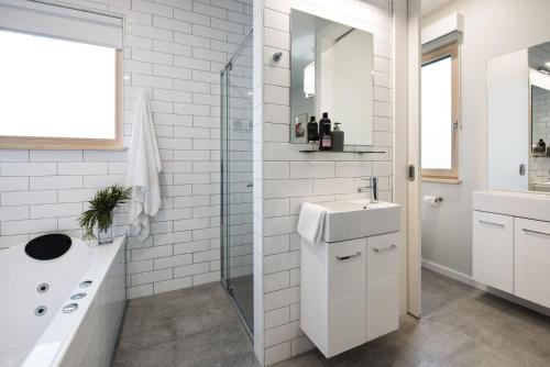 Baño blanco con lavabo y espejo en Green Retreat Passive House, en Hepburn Springs