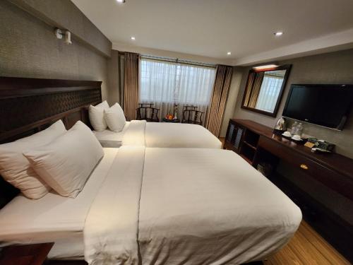 a hotel room with two beds and a flat screen tv at Classic Street Hotel in Hanoi