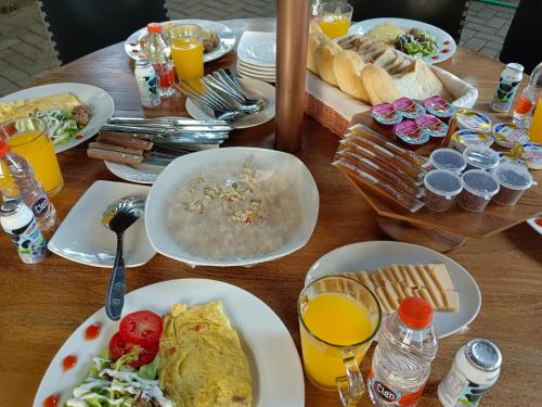 una mesa de madera cubierta con platos de comida y bebida en Valhalla Bed & Breakfast en Salatiga
