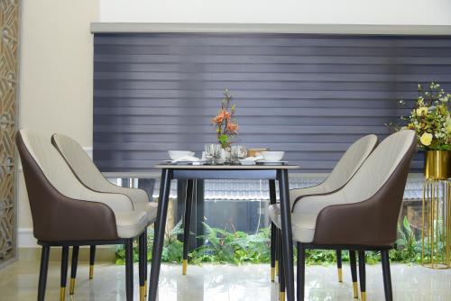 a table with three chairs and a table with flowers on it at Hera Luxury Hotel in Ho Chi Minh City