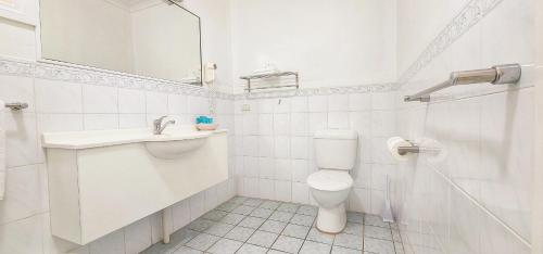 a white bathroom with a toilet and a sink at Golf Club Motor Inn Wingham in Wingham