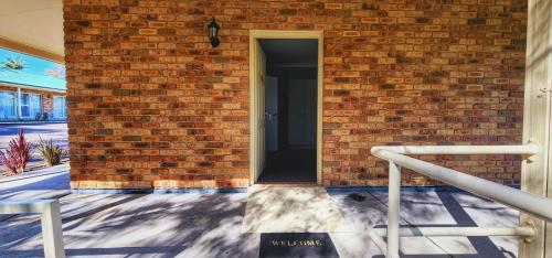 a brick wall with a door into a building at Golf Club Motor Inn Wingham in Wingham