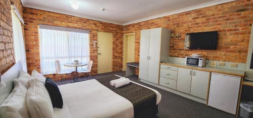 a bedroom with a bed and a brick wall at Golf Club Motor Inn Wingham in Wingham