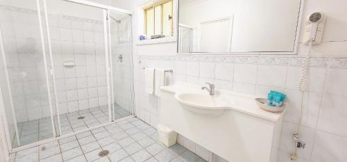 a white bathroom with a sink and a shower at Golf Club Motor Inn Wingham in Wingham