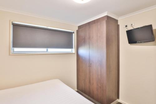 a bedroom with a bed and a tv and a cabinet at Boulevard Motor Inn in Mildura