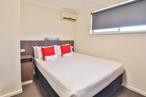 a bedroom with a large bed with red pillows at Boulevard Motor Inn in Mildura