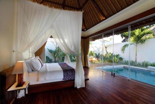 1 dormitorio con cama y piscina en Avery Le Nixsun Villas Uluwatu by Waringin Hospitality, en Uluwatu