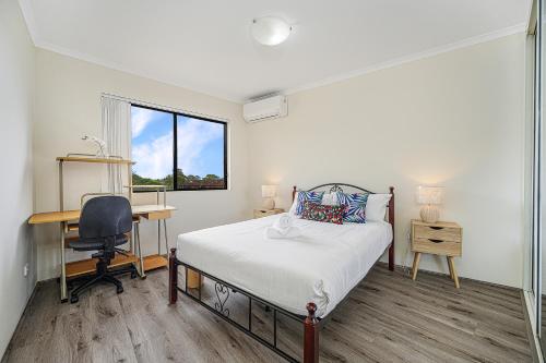 a bedroom with a bed and a desk and a window at Campsie Adorable 3Br Apt with Wifi & Parking in Sydney