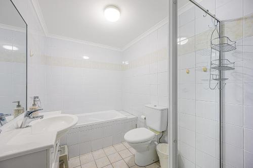 a white bathroom with a sink and a toilet at Campsie Adorable 3Br Apt with Wifi & Parking in Sydney