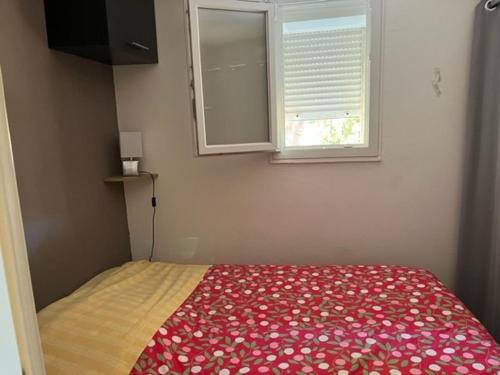 a bedroom with a bed with a red blanket and a window at Appartement Cap d'Agde, 3 pièces, 4 personnes - FR-1-749-9 in Cap d'Agde