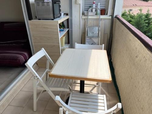 une table et deux chaises assises sur un balcon dans l'établissement Studio Cabine Climatisé pour 4 avec Parking, à 10 min de la Plage, WIFI et Animaux Acceptés - FR-1-749-5, au Cap d'Agde