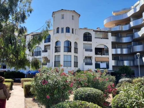 un bâtiment avec des fleurs devant lui dans l'établissement Studio Cabine 4 Pers avec Terrasse, Face Mer, Accès Direct Plage, Proche Commerces et Parc Aqualand - FR-1-81-600, au Barcarès
