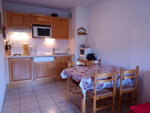 une cuisine avec une table et des chaises et une cuisine avec un four micro-ondes dans l'établissement Appartement cosy avec terrasse - 6 pers, proche pistes et commerces, parking inclus - FR-1-595-81, à Notre-Dame-de-Bellecombe