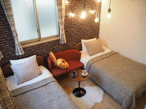 a small bedroom with two beds and a chair at City Oasis in Tokyo