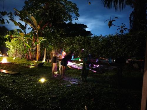eine Gruppe von Menschen, die nachts im Gras stehen in der Unterkunft Nomada Hostel in Leticia