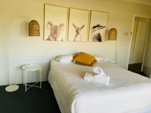 a bedroom with a bed with four pictures on the wall at The Bungalow - Wave Rock Short Stay in Hyden