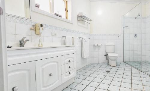 a white bathroom with a sink and a toilet at Golf Club Motor Inn Wingham in Wingham