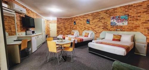 a hotel room with two beds and a table and chairs at Golf Club Motor Inn Wingham in Wingham