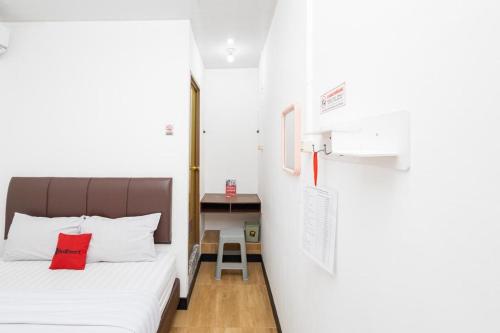 a bedroom with a bed with a red pillow at RedDoorz @ Tanjung Sari Surabaya in Tandjung-lor