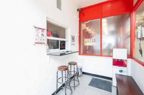 a restaurant with two stools and a red window at RedDoorz @ Tanjung Sari Surabaya in Tandjung-lor