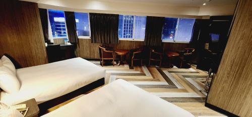 um quarto de hotel com duas camas e uma mesa e cadeiras em Gugis Inn em Taipei