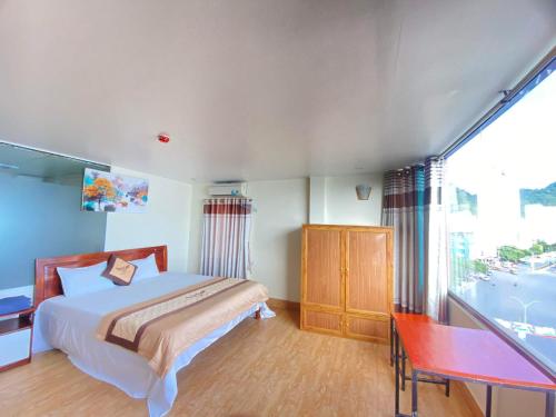 a bedroom with a bed and a desk and a window at Cat Ba Victory Hostel in Cat Ba