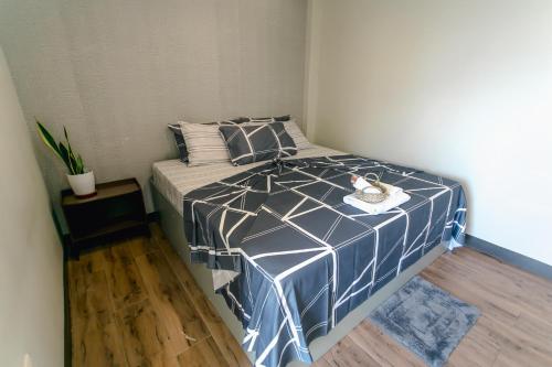 a bedroom with a bed with a blue and white comforter at Midway Stay Apartments Dumaguete in Dumaguete