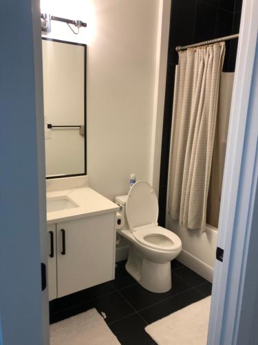 La salle de bains est pourvue de toilettes, d'un lavabo et d'un miroir. dans l'établissement Room in a New Guest House, à Fort Saskatchewan