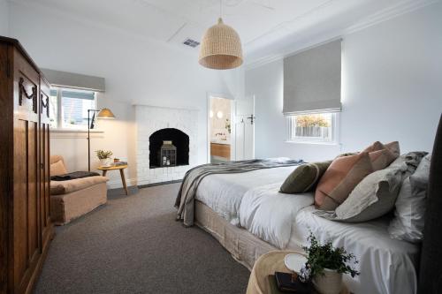 a white bedroom with a bed and a fireplace at Hambleden in Daylesford