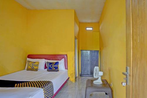 ein Schlafzimmer mit 2 Betten und einer gelben Wand in der Unterkunft SPOT ON 92827 Anisah Adil Homestay Syariah in Banyuwangi