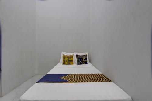 a small bed in a white room with two pillows at SPOT ON 92828 Galih Kost 1 Syariah in Grobogan