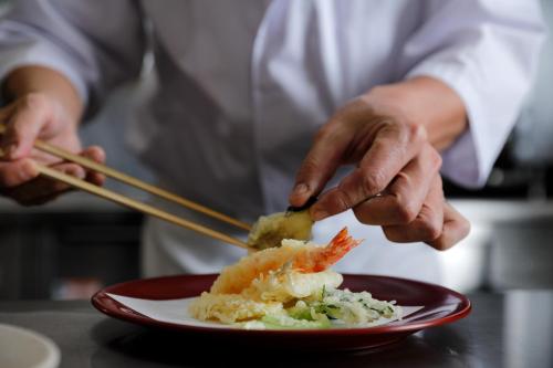 a chef is preparing a plate of food with chopsticks at The Westin Miyako Kyoto in Kyoto