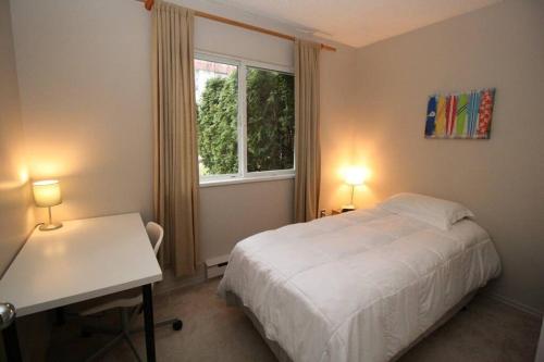a bedroom with a bed and a desk and a window at Kitsilano Beach Executive Condo in Vancouver