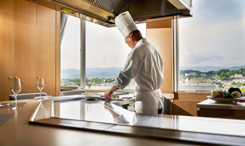 a chef standing in a kitchen preparing food at The Westin Miyako Kyoto in Kyoto