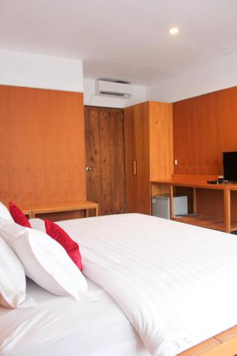 a bedroom with a large white bed with red pillows at Natuna Dive Resort in Ranai