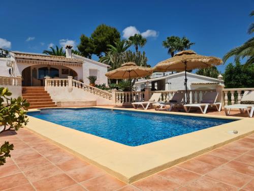 a swimming pool with umbrellas next to a house at Casa Wens Bénimeit in Moraira