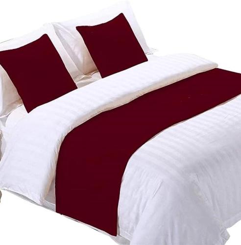 ein großes Bett mit roter und weißer Bettwäsche und Kissen in der Unterkunft Wayu Nova Guesthouse in Bulbula