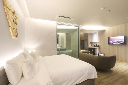 a bedroom with a white bed and a chair at The Signature Hotel Airport in Hat Yai