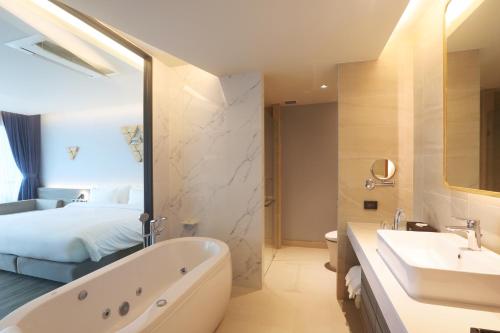 a bathroom with a tub and a sink and a bed at The Signature Hotel Airport in Hat Yai