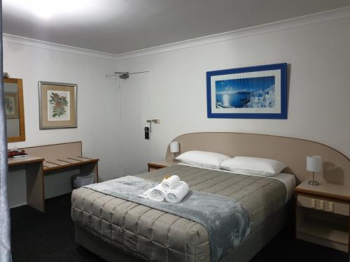 a hotel room with a bed with towels on it at Forstay Motel in Forster