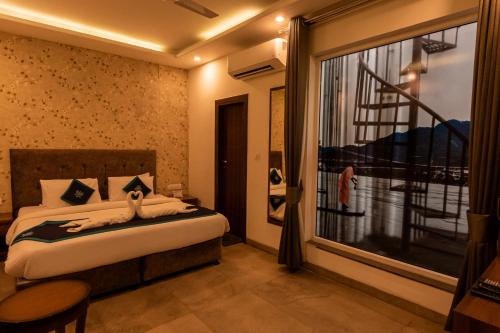 um quarto com uma cama e uma grande janela em HOLYWATER by Ganga Kinare em Rishikesh