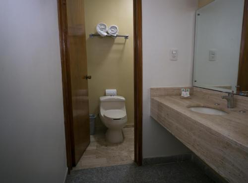 a bathroom with a toilet and a sink and a mirror at Olmeca Plaza Urban Express in Villahermosa