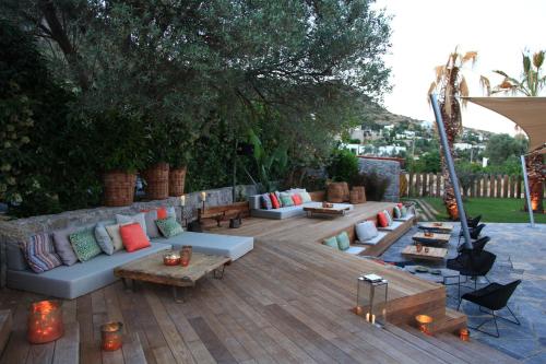 un patio con sofás y mesas en una terraza de madera en Bella Sombra, en Golturkbuku