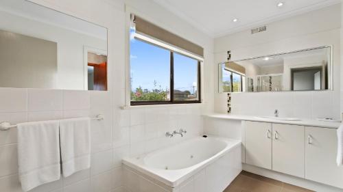 Un baño blanco con bañera y lavabo. en Cunninghame Views, en Lakes Entrance