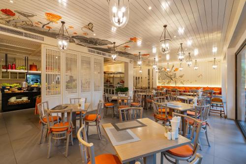 a restaurant with tables and chairs in a room at Proud Phuket, Naiyang Beach in Nai Yang Beach
