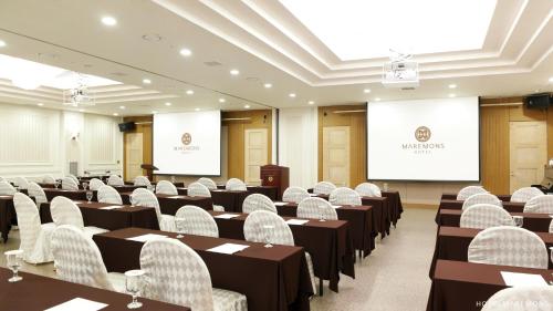 a conference room with tables and chairs and a screen at Hotel Maremons in Sokcho